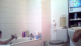 Brunette relaxes in bath and plays with her body